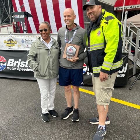 BMS Vice President of Corporate Sales Chipper Harvey (middle) receives a commemorative plaque from Tri-Cities 9-11 Memorial Stair Climb organizer Andrew Catron (right) in appreciation of the track's fifth year of hosting the event that honors fallen first responders. This is the 10th year of the event in the Tri-Cities region.